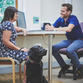 Dave Dickson sat across from a female at a table with a black labrador dog