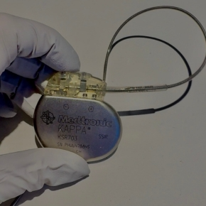 A gloved hand holding a pacemaker