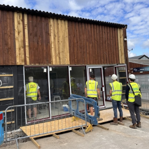 Building site entrance of the new clinic with workmen in high-vis jackets